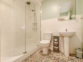 A bathroom with a shower, toilet, sink and storage unit at Rails End