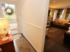 A hallway with a door, rug, lamp, and view of a living room at Jodene Lodge, Redwood 2 in Bowness-On-Windermere