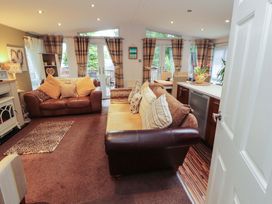A living room with a sofa and dining area at Jodene Lodge, Redwood 2 Bowness-On-Windermere