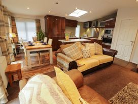 An open plan living area with a kitchen and dining table at Jodene Lodge, Bowness-On-Windermere