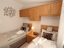 A bedroom with two beds and a nightstand at Jodene Lodge, Redwood 2, Bowness-On-Windermere