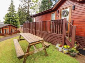 A wooden picnic table and flower pots outside a cabin at Jodene Lodge, Redwood 2 Bowness-On-Windermere