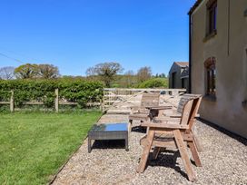 A patio with wooden chairs and a coffee table at The Annexe at Dalby Carr