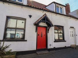 A house exterior with a red front door and windows at Fleming Cottage