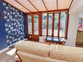 A conservatory with a sofa and windows at Fleming Cottage