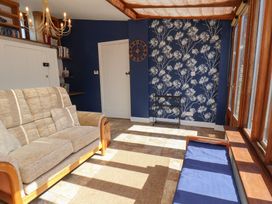 A snug with a sofa and a wall clock at Fleming Cottage