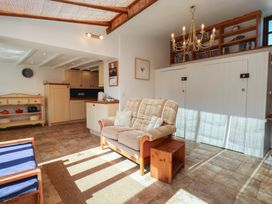 A living room with a sofa and kitchen area at Fleming Cottage