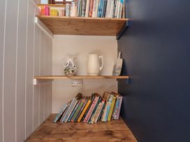 A bookshelf with books and jugs in a library at Fleming Cottage