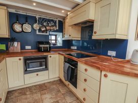 A kitchen with cabinets, countertop, microwave, and various cooking utensils at Fleming Cottage