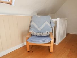 A chair with a blanket on it in a sitting area at Fleming Cottage