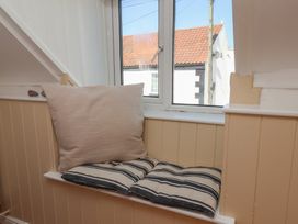 A seating area with cushions by a window at Fleming Cottage