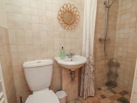 A bathroom with a shower, toilet, mirror, and sink at Fleming Cottage
