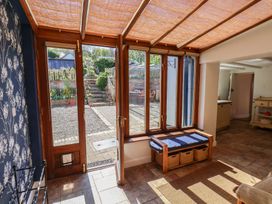 A conservatory with wooden doors and storage bench at Fleming Cottage