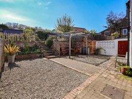 A garden with a gravel area, a pergola, a table, and chairs at Fleming Cottage in 