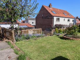 A garden with a tree and fence at Fleming Cottage
