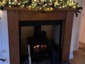 A fireplace with a wood stove and garland at Fleming Cottage in Hunmanby