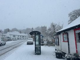 A bus stop on a snowy road with buildings in the background at Fleming Cottage Hunmanby