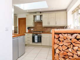 A kitchen with a stove and wood storage at Tinners Way in Helston