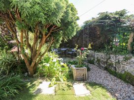 A garden with a tree, table, chairs and flowers at Tinners Way in Helston