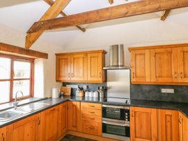 A kitchen with wooden cabinets and stainless steel appliances at Maerdy Cwtch Haverfordwest