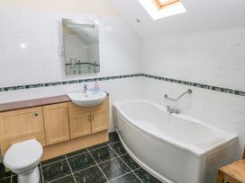 A bathroom with a bath tub, toilet, sink and cabinet at Maerdy Cwtch in Haverfordwest