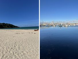 A beach with sand and water beside a harbor with fishing boats at Dog-friendly lodge, steps to St Ives train Hayle