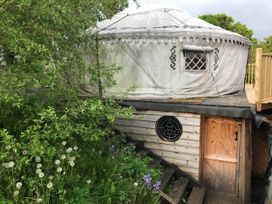 An outdoor yurt structure with a wooden door and surrounding plants at Hapus Yurt - Two Beautiful Yurts and Barn Cottage
