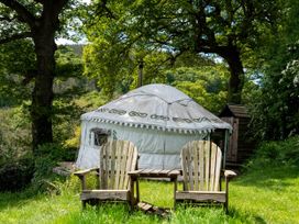 An outdoor area with a yurt and wooden chairs at Hapus Yurt - Two Beautiful Yurts and Barn Cottage