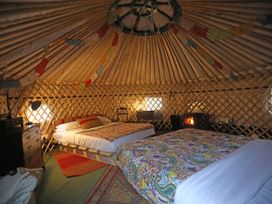 A bedroom with two beds and a stove at Hapus Yurt - Two Beautiful Yurts and Barn Cottage