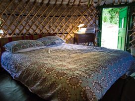 A bedroom with a bed and nightstand at Hapus Yurt - Two Beautiful Yurts and Barn Cottage