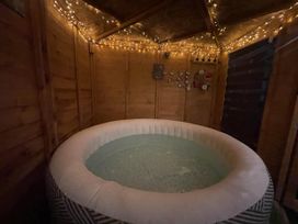 A hot tub in a wooden cabin with string lights at Zip Cottage Sleeps 2-3 climb snowdon zip world