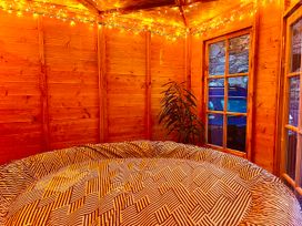 A garden room with a round bed and wooden walls at Zip Cottage Sleeps 2-3 climb snowdon zip world