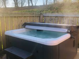 A hot tub with a cover in a garden area at Pet-friendly lodge with hot tub near the coast