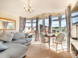 A living room with sofa and dining table at Pet-friendly lodge with hot tub near the coast