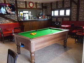 A snug area with a pool table and a bar counter at Pet-friendly lodge with hot tub near the coast