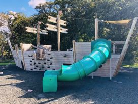 A playground structure shaped like a ship with a slide at a park