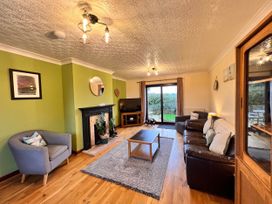 A living room with a sofa, coffee table, and television at Dog-friendly farmhouse with Menai Strait views