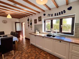 A kitchen with sink and dining table at Dog-friendly farmhouse with Menai Strait views 