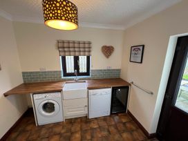 A kitchen with a sink, dishwasher, washing machine and a fridge at Dog-friendly farmhouse with Menai Strait views