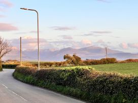 A view of mountains and a road with hedges at Dog-friendly farmhouse with Menai Strait views