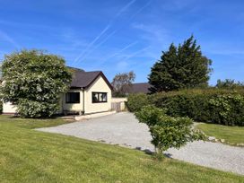 A house with a gravel driveway and trees outside Cottage with mountain and sea views, Anglesey