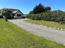 A house with a gravel driveway and grass area at Cottage with mountain and sea views, Anglesey