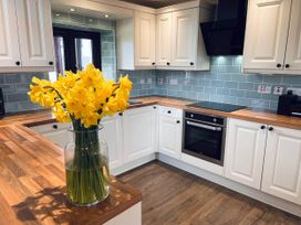 A kitchen with cabinets and a vase of flowers at Cottage with mountain and sea views, Anglesey