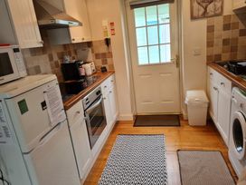 A kitchen with appliances and a door at Riverside cottage with otters near Tintagel