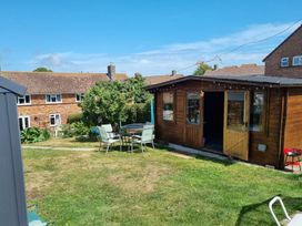 A garden with a wooden shed and table with chairs at tbc in 