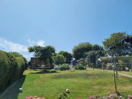 A garden with flowers, trees, a shed, and a soccer ball at tbc