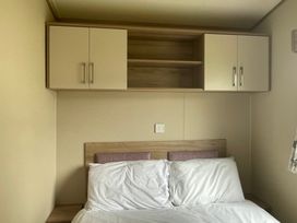 A bedroom with a bed and wall-mounted cabinets at tbc 