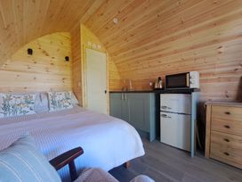 A bedroom with a bed and small kitchen area at tbc