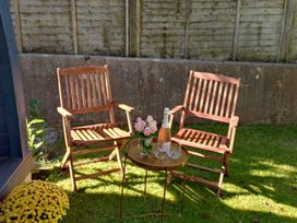 Two chairs and a table with a bottle and glasses in a garden at tbc