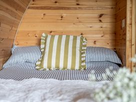 A bed with striped bedding and a decorative pillow at Peaceful pod with bay views, walk to 3 beaches in St Ives
